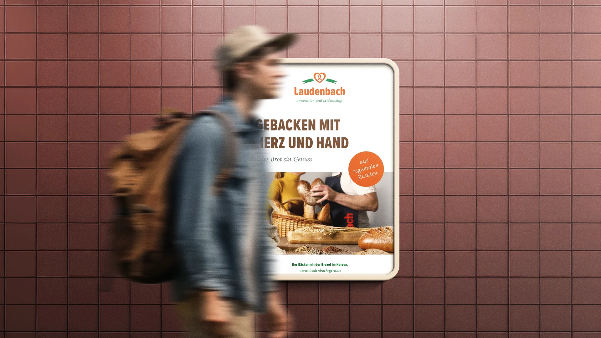 Plakatmotiv der Bäckerei Laudenbach mit der Botschaft „Gebacken mit Herz und Hand“ und Brotvielfalt im Vordergrund, platziert in einer U-Bahn-Station.