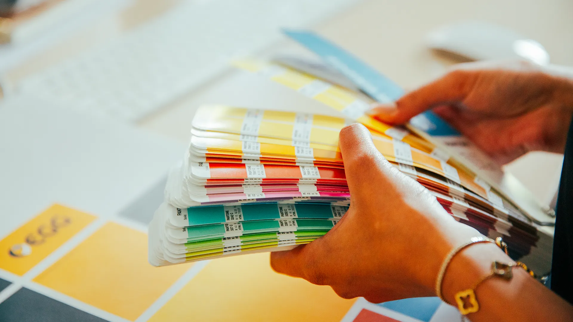 Hände blättern durch einen Farbfächer mit Pantone-Tönen zur Abstimmung des Corporate Designs – präzise Farbberatung bei Trendsetzer.