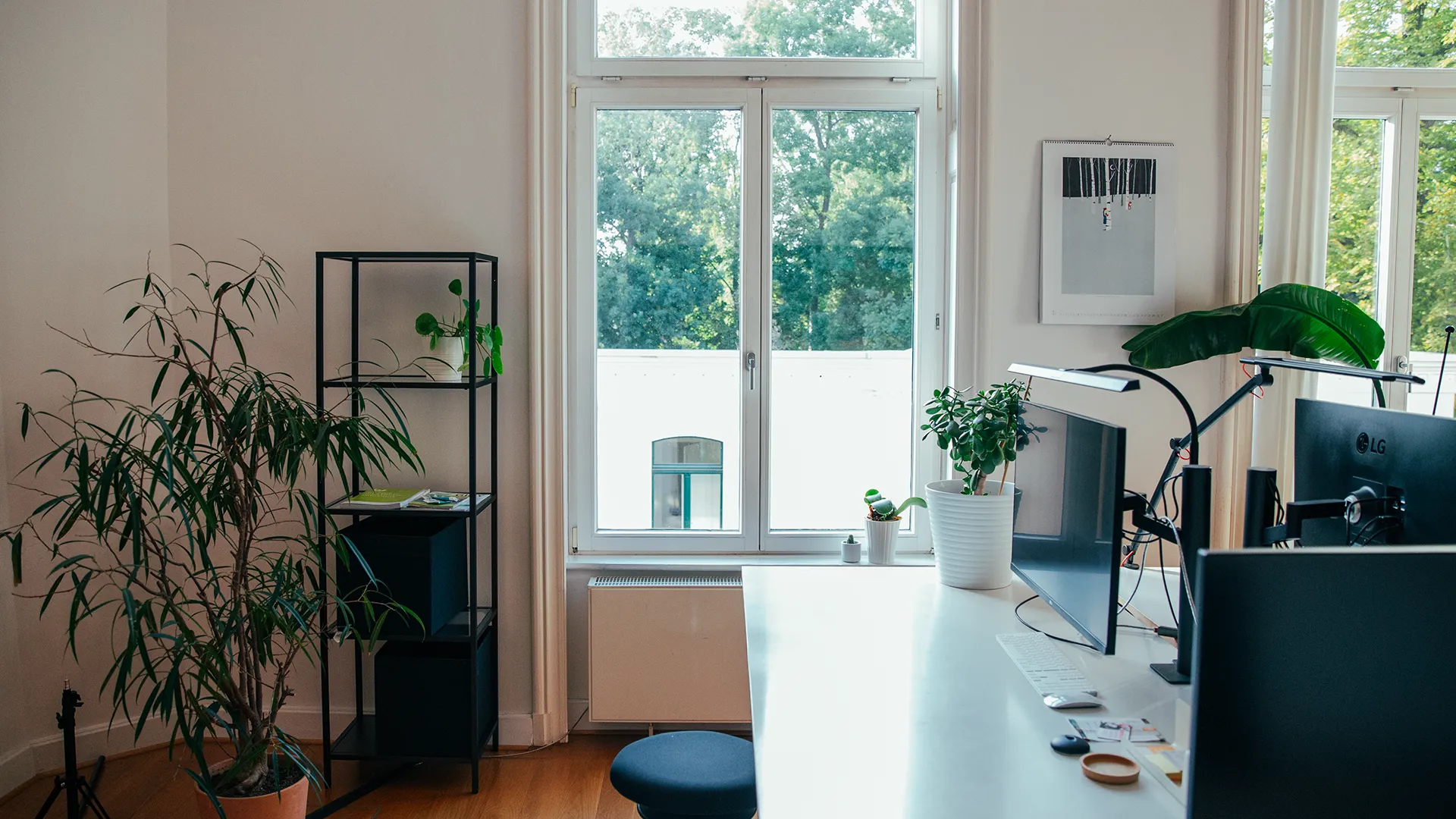 Blick auf den Arbeitsplatz bei Trendsetzer Leipzig mit großen Fenstern, Monitoren und Pflanzen in heller Atmosphäre.