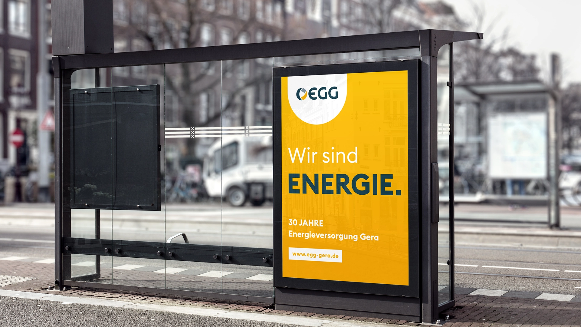 Citylight-Plakat der Energieversorgung Gera an einer Haltestelle mit Claim „Wir sind Energie.“ in Gelb und Blau.