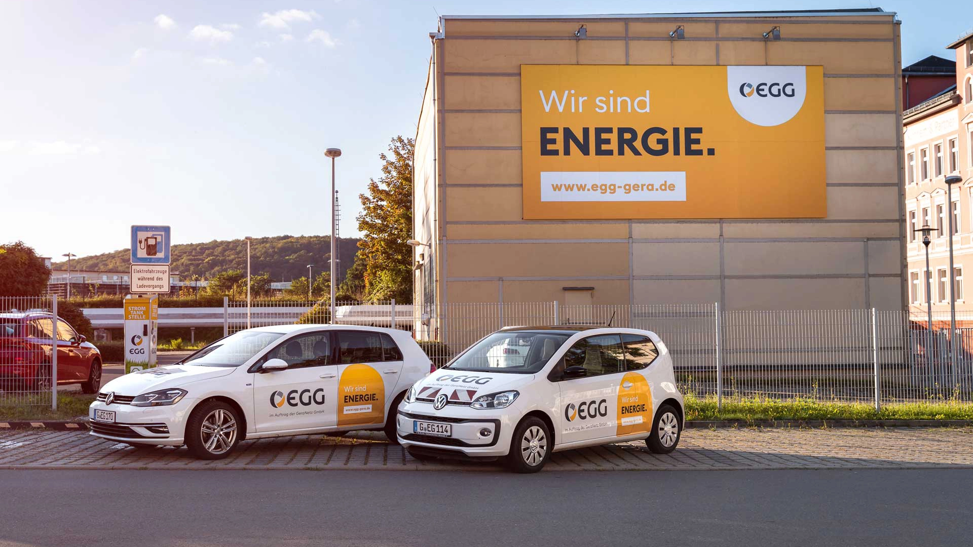 Fahrzeuge der Energieversorgung Gera mit Claim „Wir sind Energie.“ vor einem Großplakat im Corporate Design.
