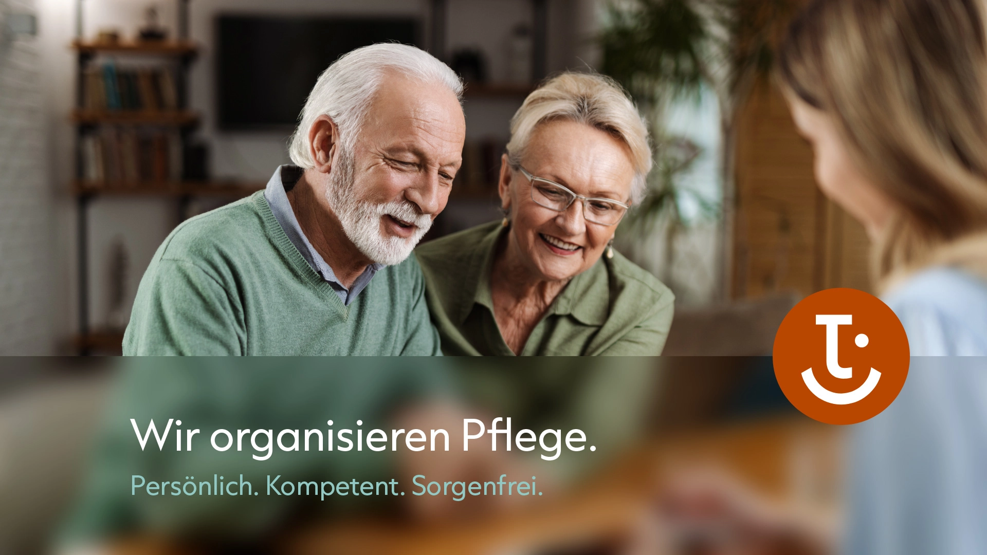 Älteres Paar im Gespräch mit einer Beraterin, eingeblendeter Slogan „Wir organisieren Pflege“ mit Valent Cura Bildmarke
